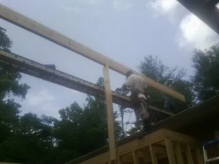 Carpenter setting a ridge beam over a new addition frame — Ice Dam Removal by Roofing Brothers in Maple Hill