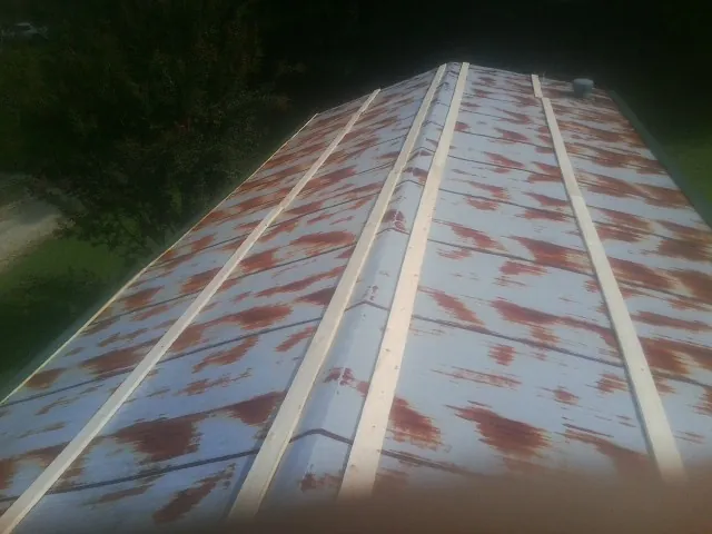Rusted metal roof panels with new wood purlins before replacement — Storm Damage Roof Repair in Maple Hill by Roofing Brothers