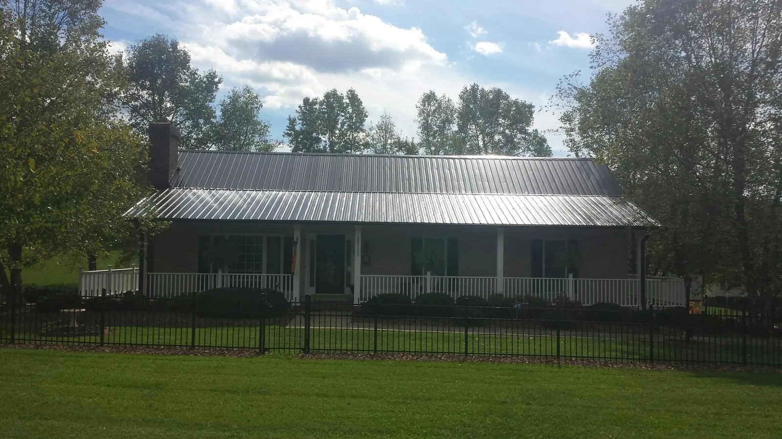 Gray metal roof on a brick ranch with a full width front porch — Gutter Guard Installation work by our crew in Maple Hill